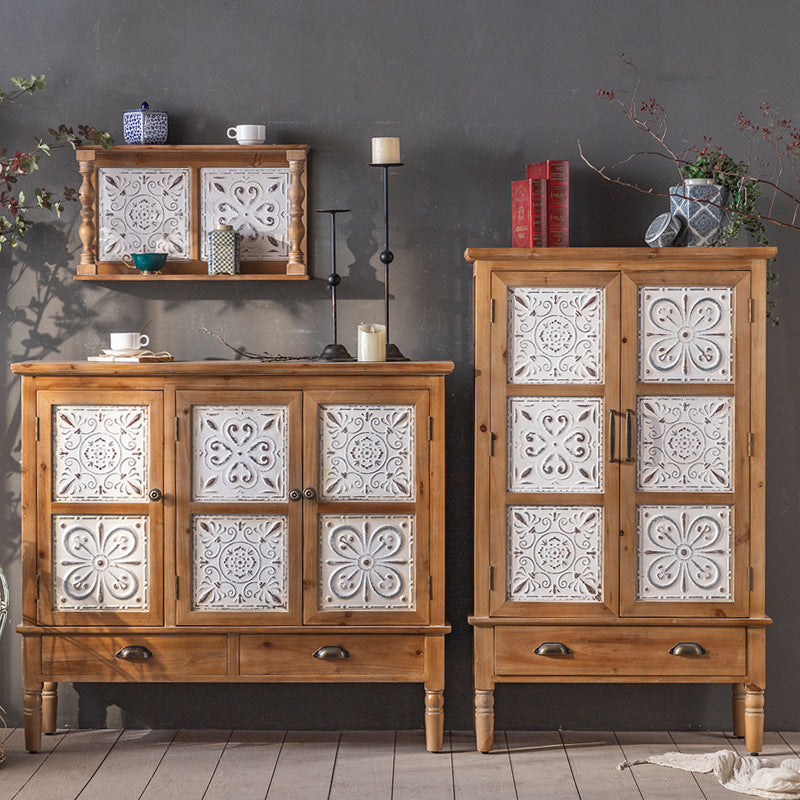 The Rustic Sideboard and Wall Shelf Set from Furnishaus showcases timeless design and charm against a gray wall. The set includes ornate white floral panel cabinets, matching shelves for plants and candles, with books and vases adding elegant touches to the cabinet tops.